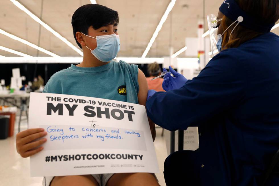 Lucas Kittikamron-Mora, 13, holds a sign in support of COVID-19 vaccinations as he receives his ...