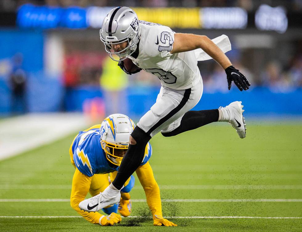 Raiders wide receiver Hunter Renfrow (13) fights for extra yardage past Los Angeles Chargers co ...