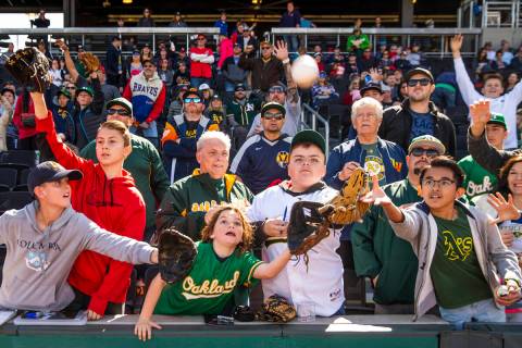 Fans work for position to catch a ball tossed by an Oakland Athletics player during a Big Leagu ...