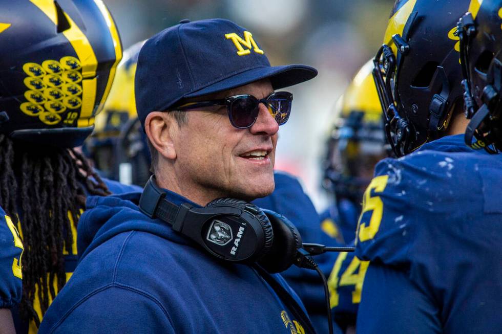 Michigan head coach Jim Harbaugh huddles with his players on the field during a time out in the ...