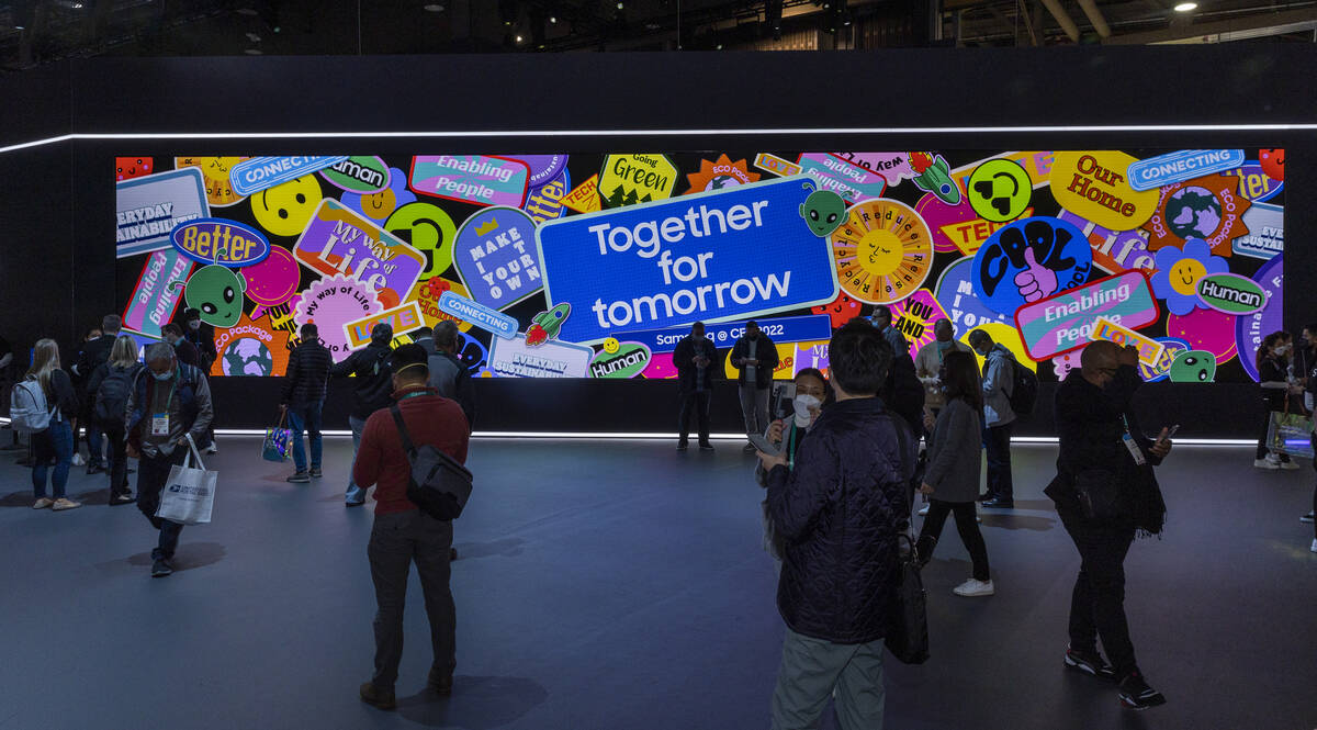 Attendees wander about the large video screen in the Samsung display area during the first day ...