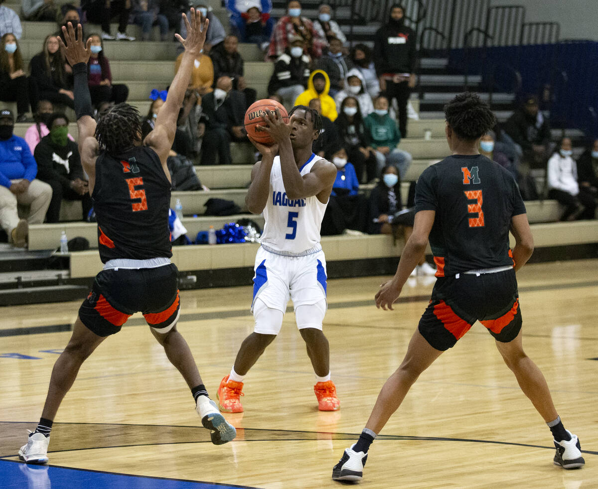 Desert Pines’ Greg Burrell (5) shoots against Mojave’s Jameer McNeal (5) and CJ S ...