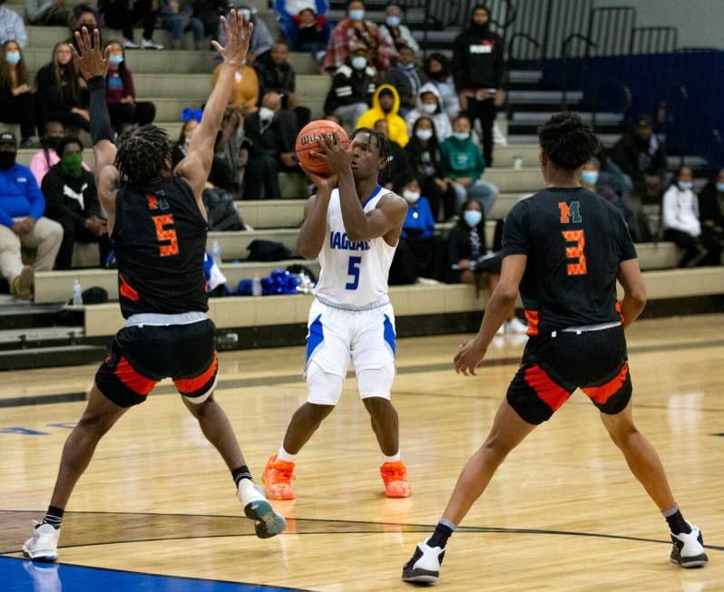 Desert Pines’ Greg Burrell (5) shoots against Mojave’s Jameer McNeal (5) and CJ S ...