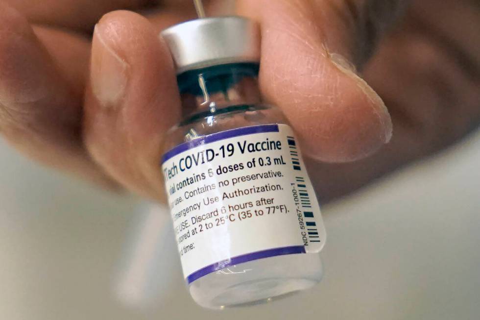 A doctor loads a dose of Pfizer COVID-19 vaccine into a syringe, Thursday, Dec. 2, 2021, at a m ...