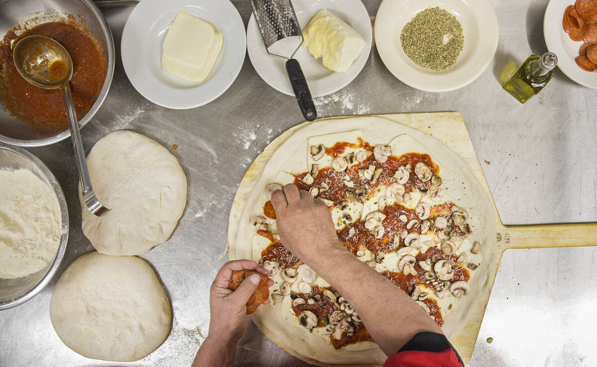 Chef/co-owner John Arena prepares an Olde New York specialty pizza, made with thick slices of m ...