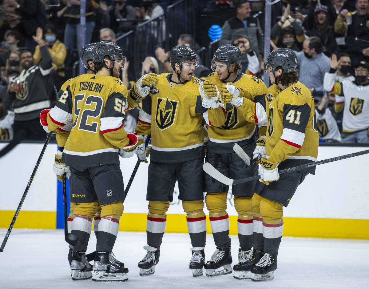 Golden Knights players help celebrate a goal by teammate defenseman Ben Hutton (17) during the ...