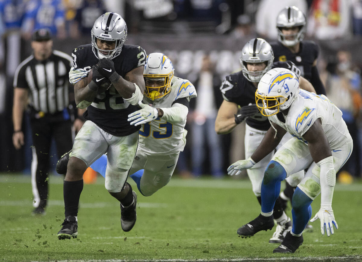 Raiders running back Josh Jacobs (28) leaps through a hole past Los Angeles Chargers free safet ...