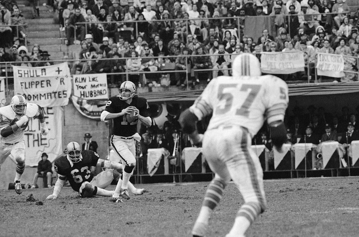 Ken Stabler, quarterback of the Oakland Raiders, looks downfield as he is pursued by Miami Dolp ...