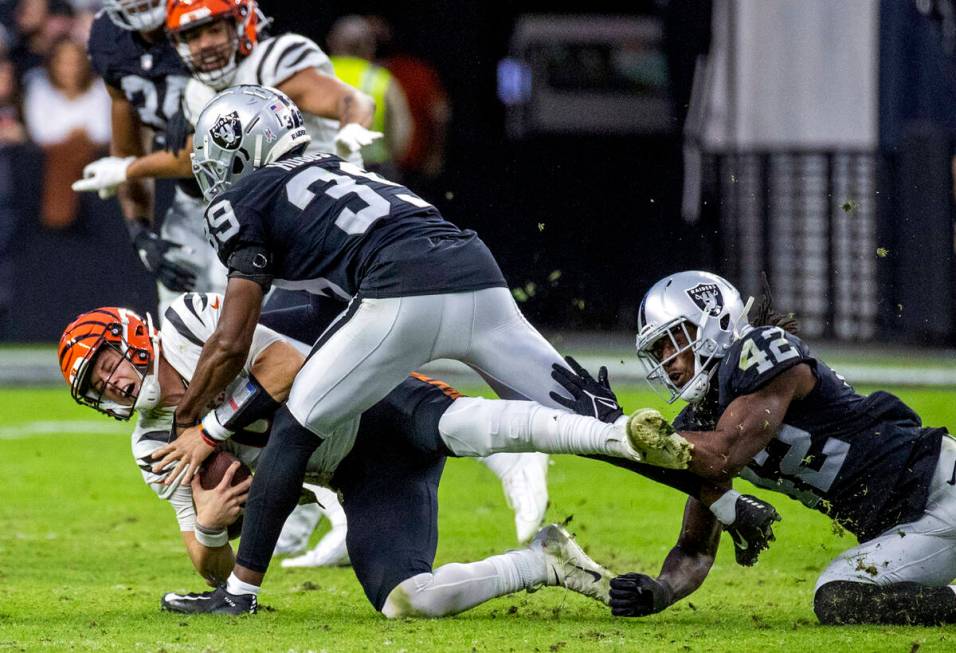 Cincinnati Bengals quarterback Joe Burrow (9) is taken down by Raiders cornerback Nate Hobbs (3 ...