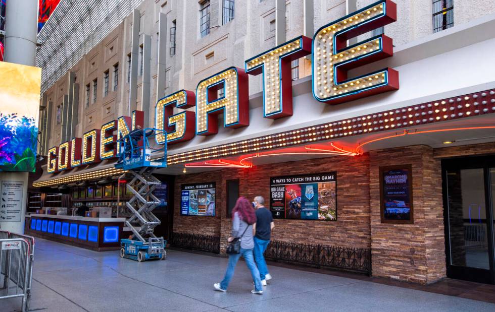 Visitors walk past the Golden Gate as Jesus Caballero cleans the lettering above, the venue is ...