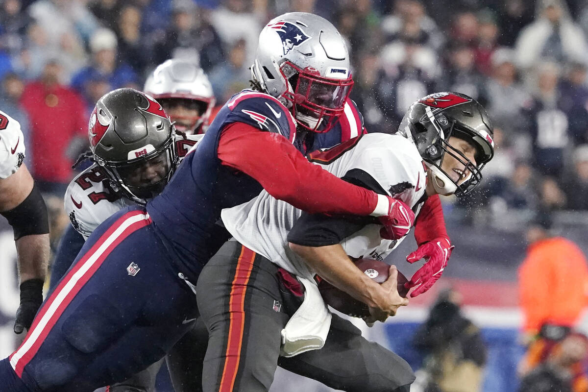 Tampa Bay Buccaneers quarterback Tom Brady, right, is sacked by New England Patriots outside li ...
