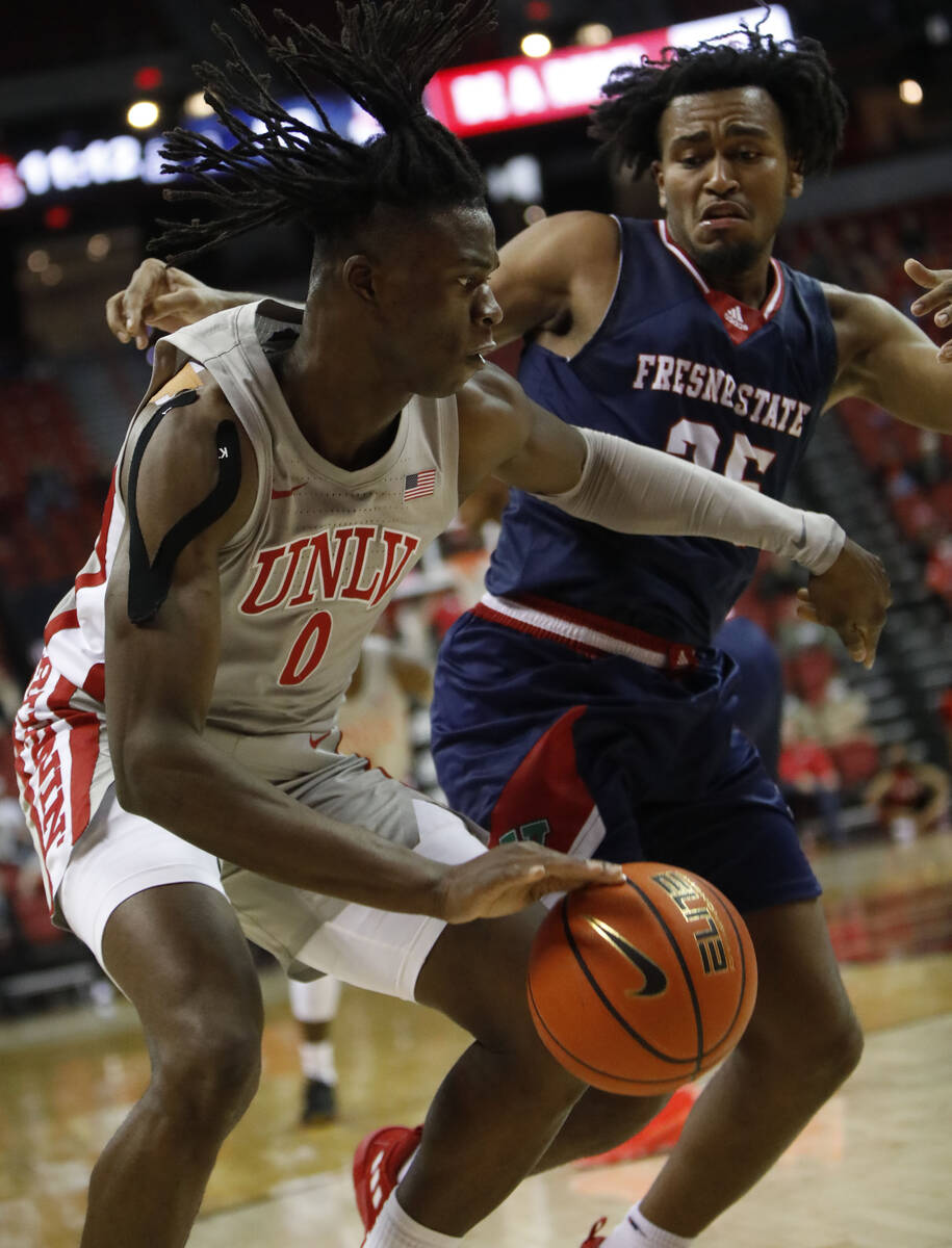UNLV Rebels forward Victor Iwuakor (0) keeps a ball away from Fresno State Bulldogs guard Anth ...