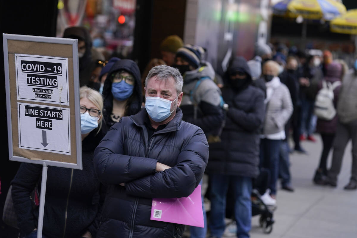 FILE - People wait in line at a COVID-19 testing site in Times Square, New York, Monday, Dec. 1 ...