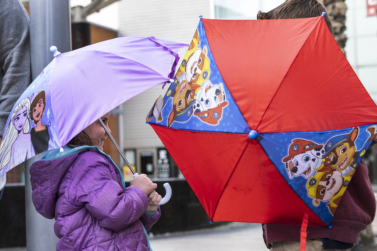 Erika Gannon, 4, left, and her brother Mason, 6, hold umbrellas to protect themselves from rain ...