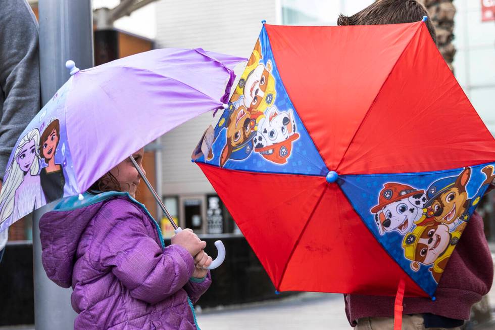 Erika Gannon, 4, left, and her brother Mason, 6, hold umbrellas to protect themselves from rain ...