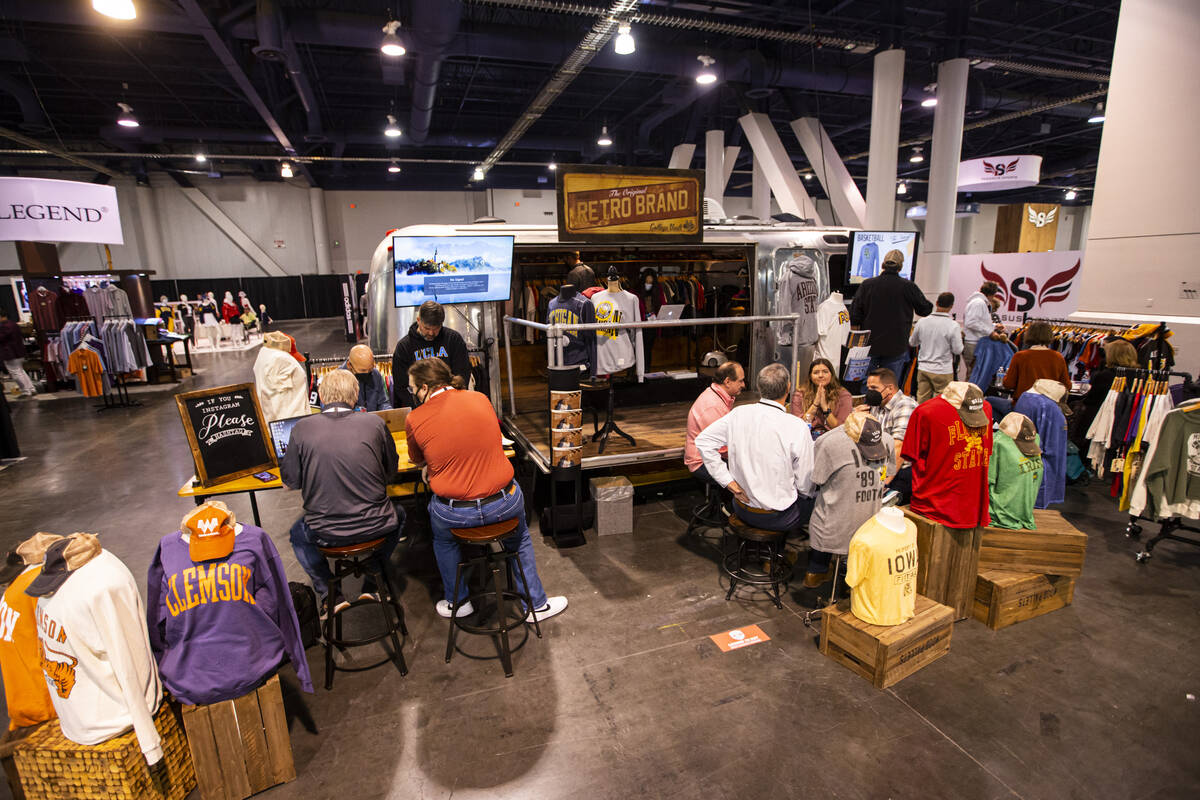 Attendees chat with representatives at the Original Retro Brand booth during the Sports Licensi ...