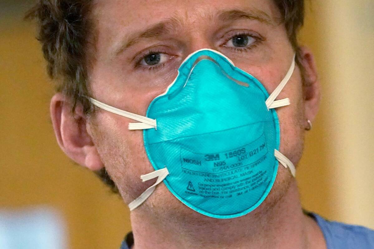 Registered nurse Scott McGieson wears an N95 mask as he walks out of a patient's room in the ac ...