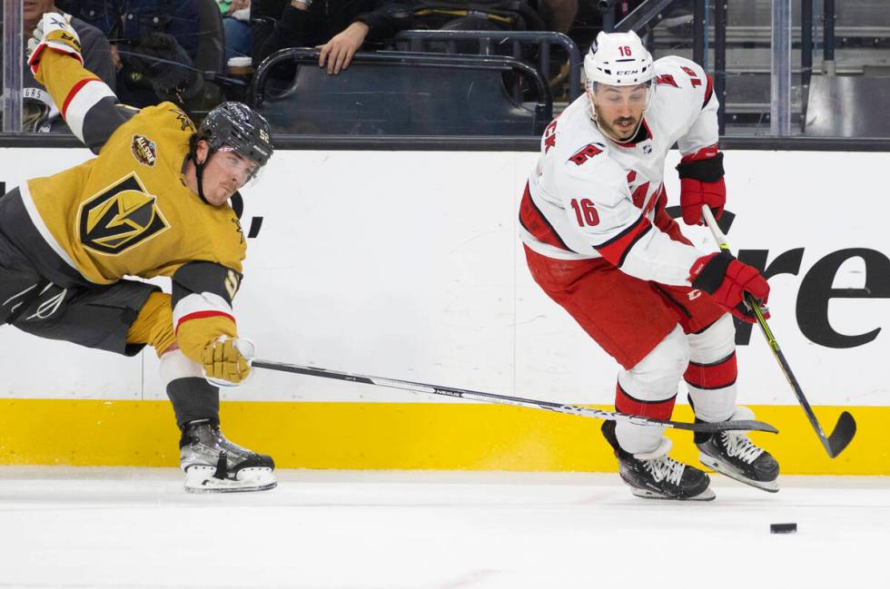 Golden Knights defenseman Dylan Coghlan (52) fights for a loose puck with Carolina Hurricanes c ...