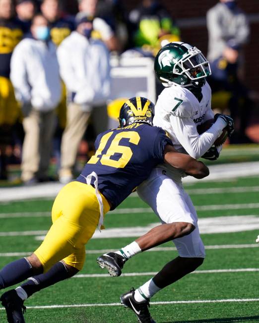 Michigan State wide receiver Ricky White (7) is tackled by Michigan defensive back Jalen Perry ...