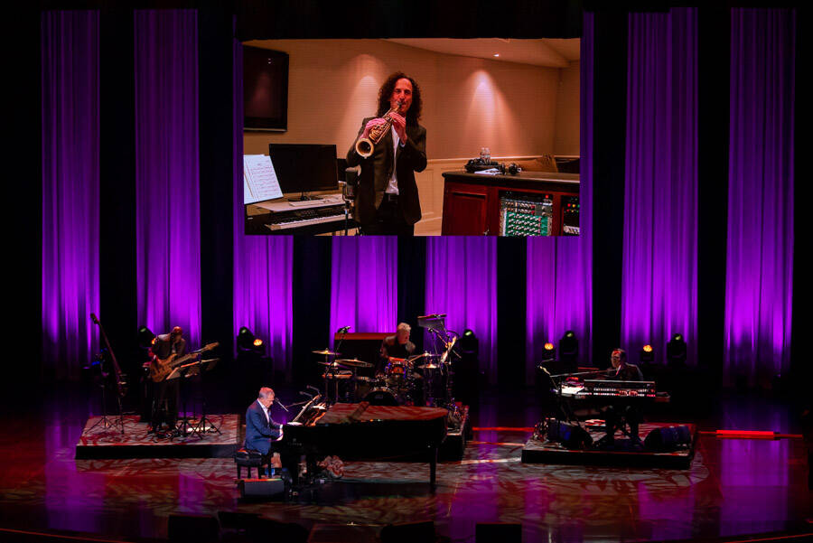 Famed producer, composer and arranger David Foster is shown with a video of Kenny G. at Encore ...