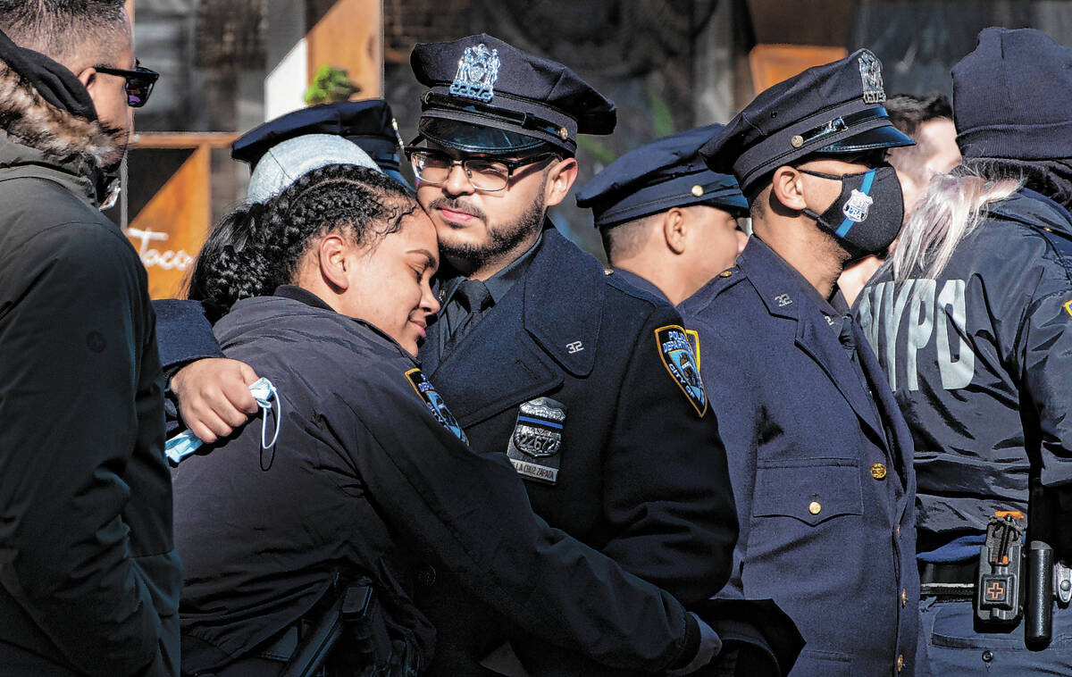 Police officers embrace after the remains of New York City Police Department Officer Wilbert Mo ...