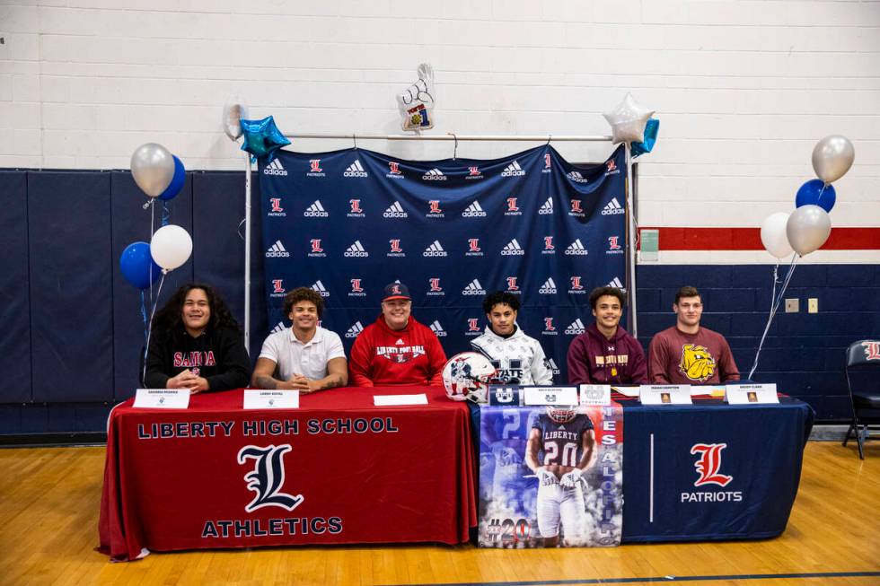 Liberty football head coach Rich Muraco, third from left, sits for a photo with players, from l ...
