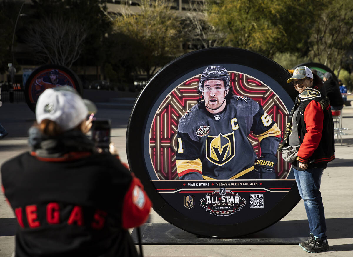 Renee Terrell, right, poses with a large puck with a photo of Golden Knights all-star Mark Ston ...