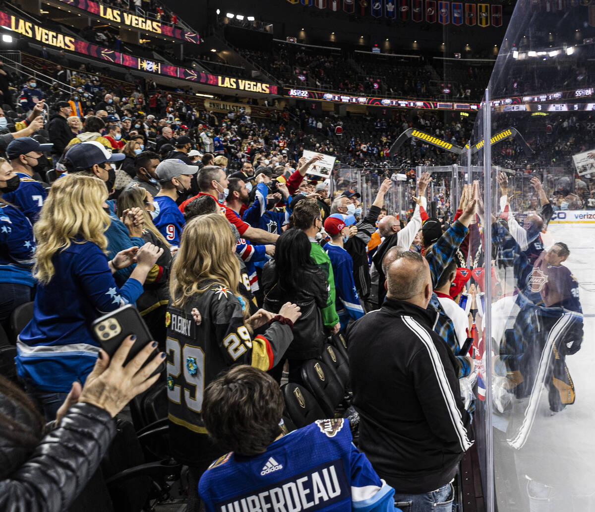 Pittsburgh Penguins goaltender Tristan Jarry, right, gives his stick to fans during the NHL All ...