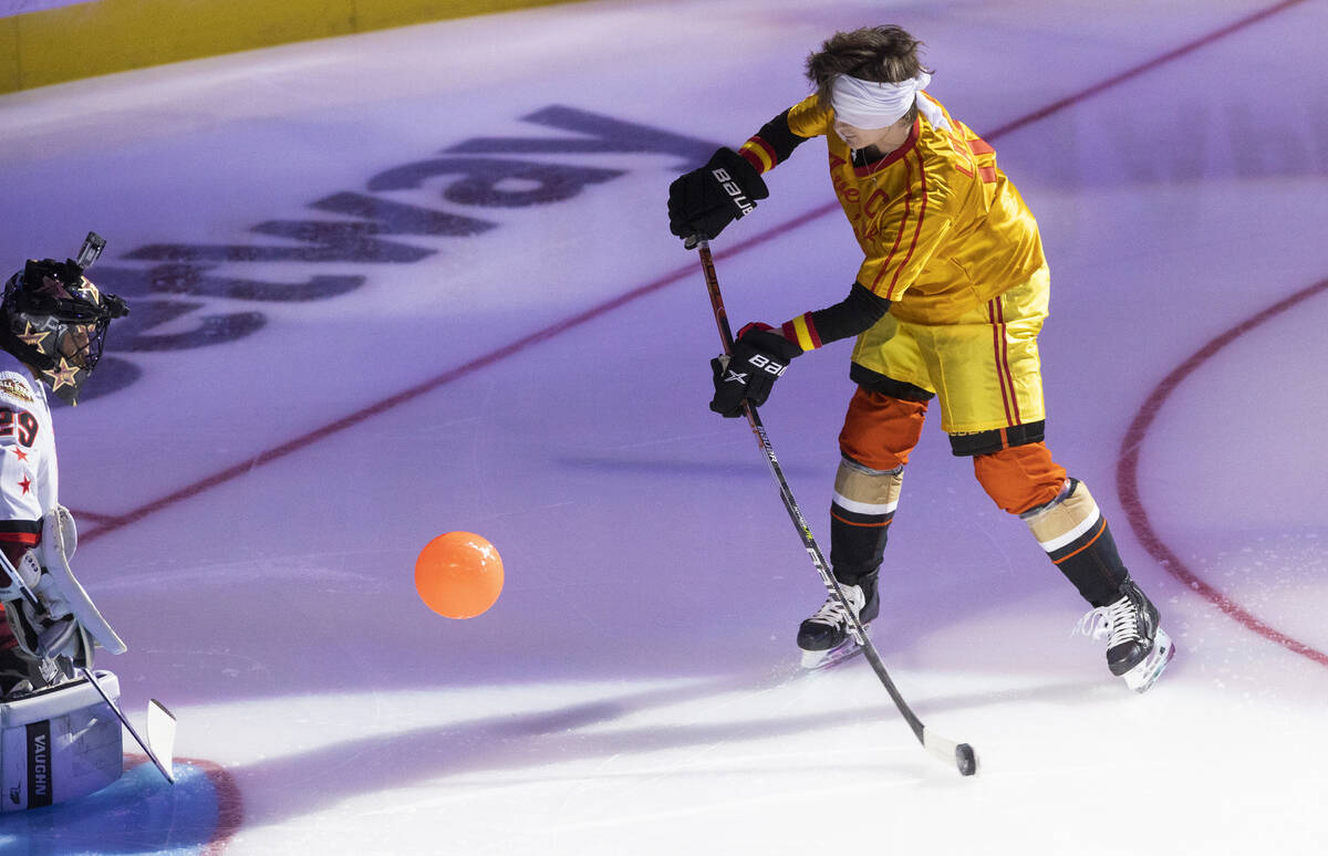 Anaheim Ducks center Trevor Zegras, right, shoots on goal while blindfolded and wearing a costu ...