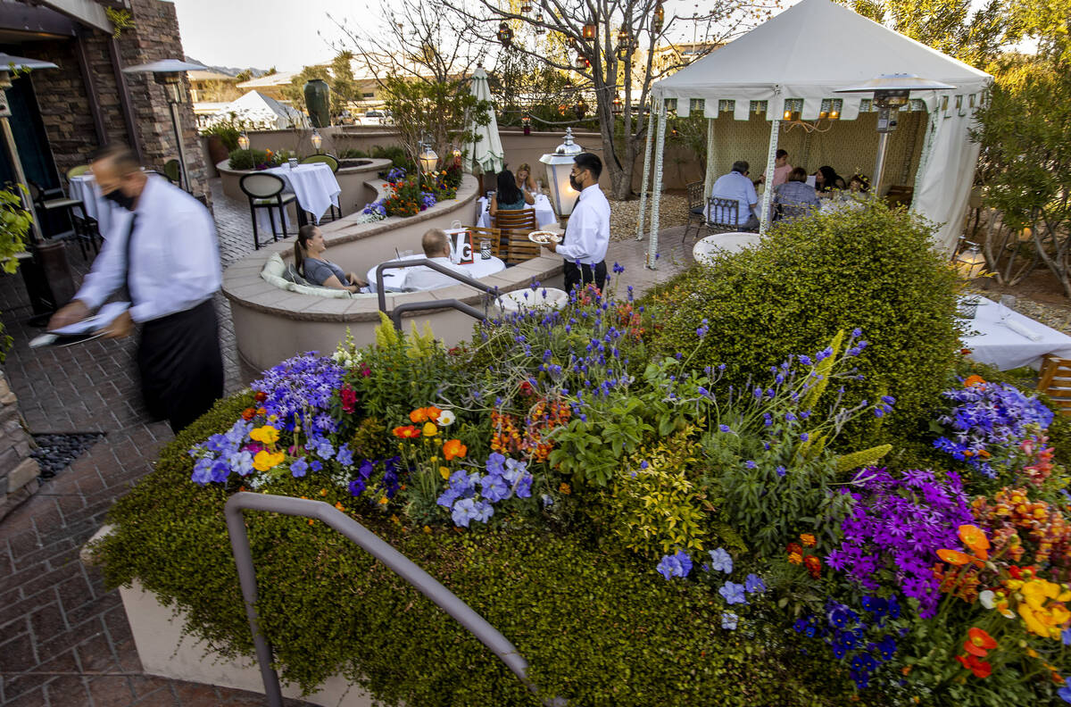 The Vintner Grill outdoor dining area welcomes guests with a flower garden, illuminated tents, ...