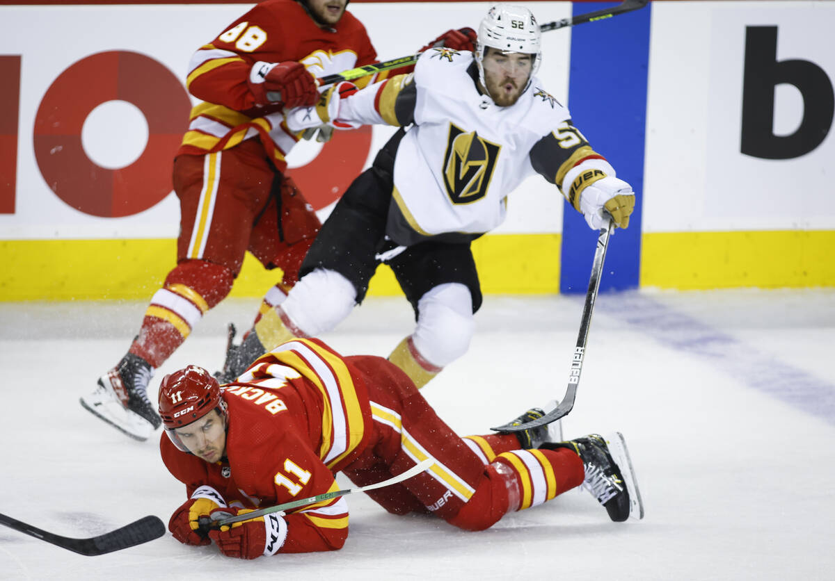 Vegas Golden Knights' Dylan Coghlan, right, crashes over Calgary Flames' Mikael Backlund during ...