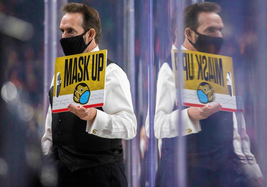 An usher holds a mask up sign during the Golden Knights Carolina Hurricanes NHL hockey game on ...