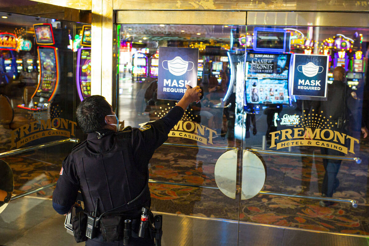 Signs requiring masks are removed by a security officer at the Fremont hotel-casino following t ...