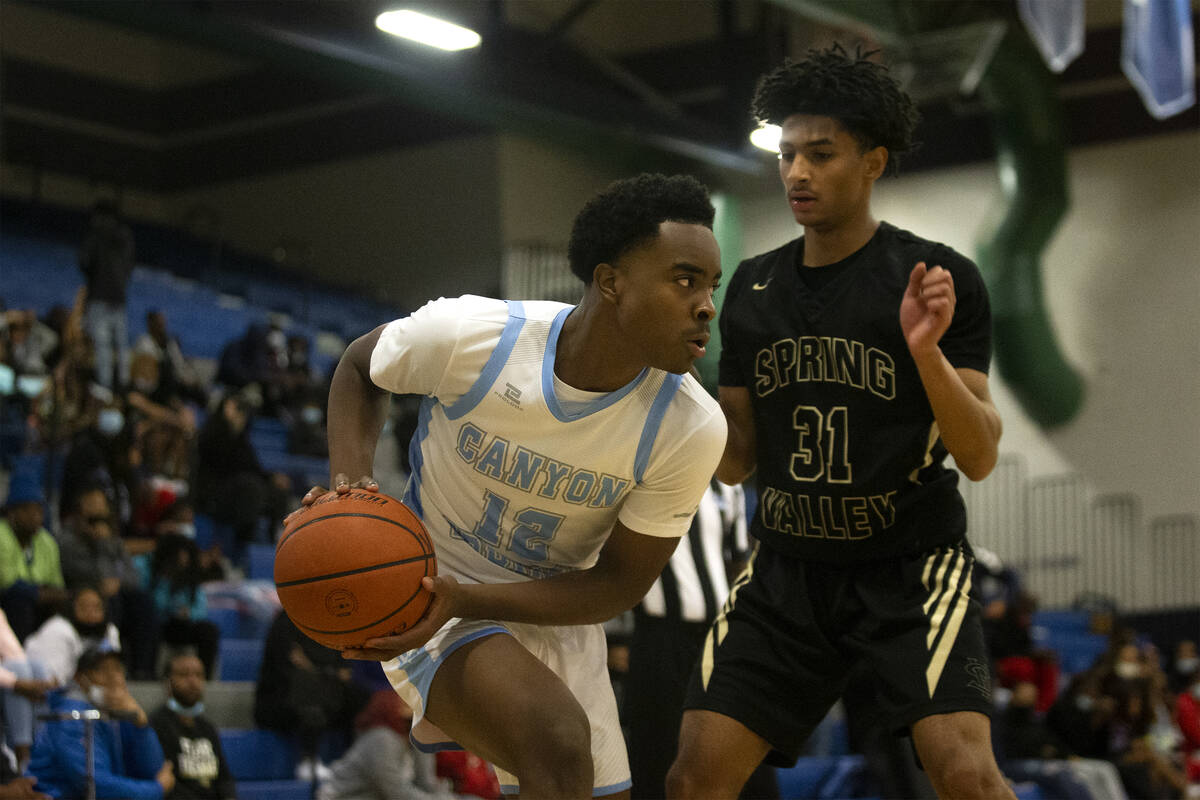 Canyon Springs forward Jaylen Pollard (12) looks to pass while Spring Valley guard Alijah Adem ...