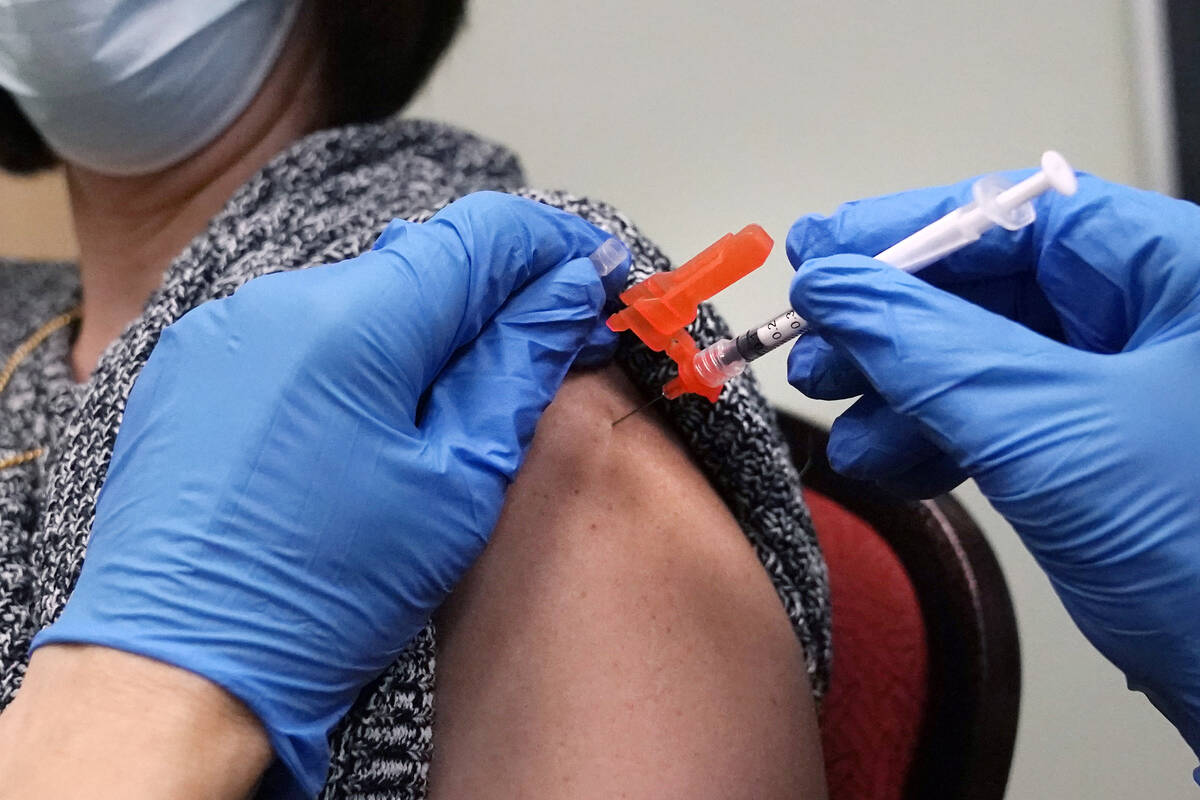 FILE - A woman receives a COVID-19 vaccine injection by a pharmacist at a clinic in Lawrence, M ...