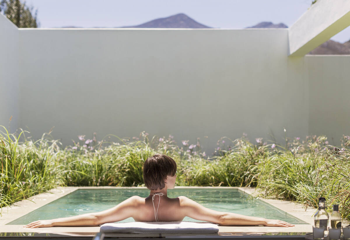 A woman relaxes in her backyard spool, a combination of a spa and pool. (Getty Images)