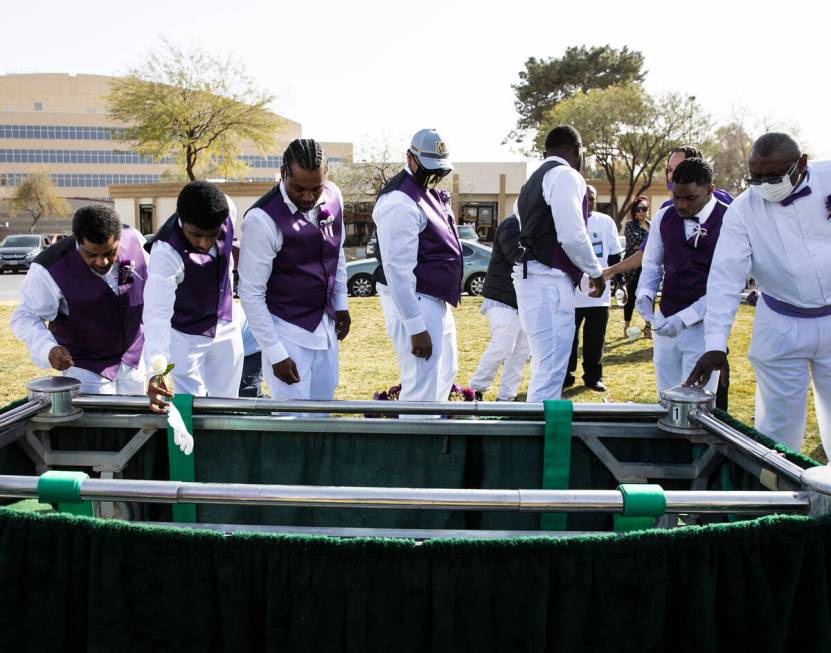 Pallbearers throw their gloves and flowers on the coffin, containing Tanaga Miller, one of 9 pe ...