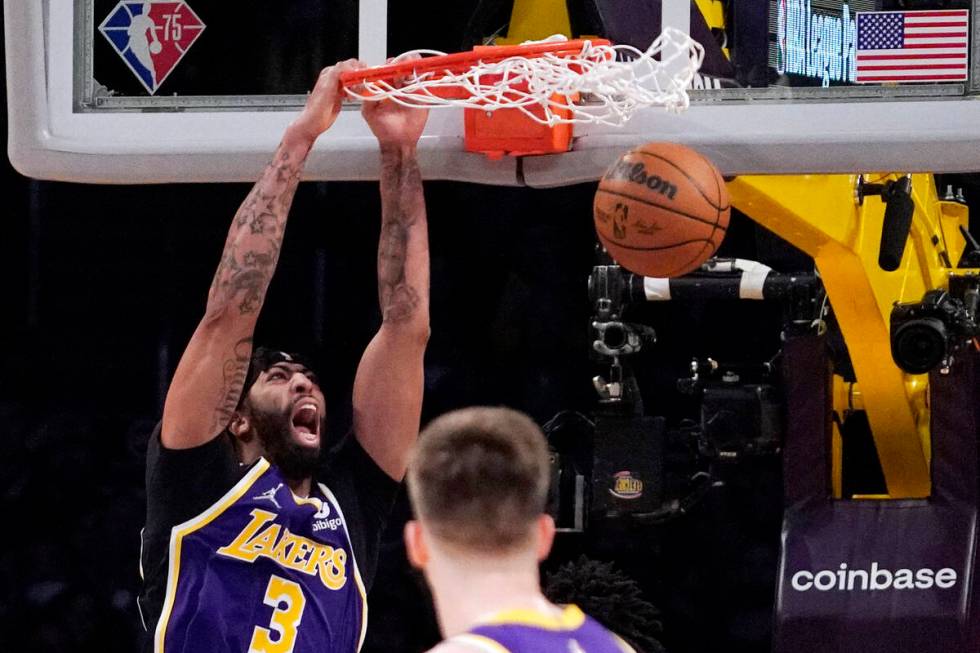 Los Angeles Lakers forward Anthony Davis, left, dunks as guard Austin Reaves watches during the ...