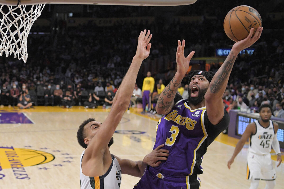 Los Angeles Lakers forward Anthony Davis, center, shoots as Utah Jazz center Rudy Gobert defend ...