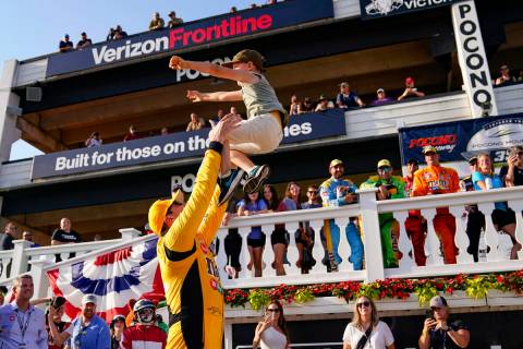 Kyle Busch, left, tosses his six-year-old son Brexton as he celebrates after winning a NASCAR C ...
