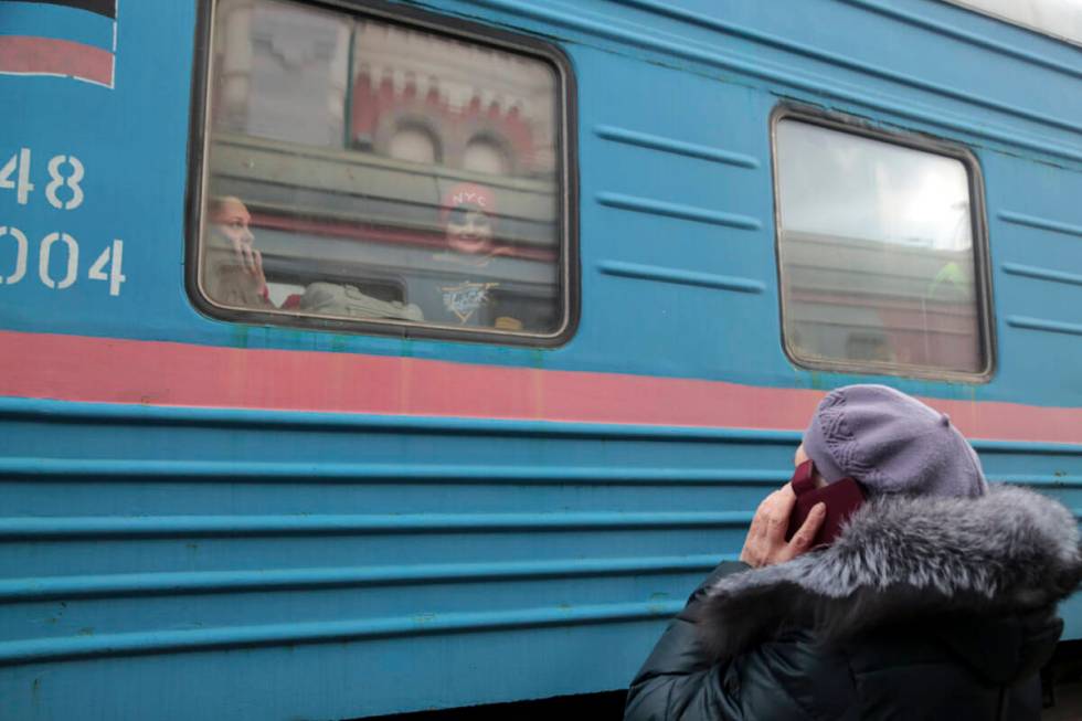 A woman speaks on the phone with her relatives as a child looks through a train window prior to ...