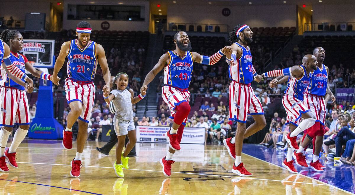 Harlem Globetrotters skip onto the court with a young fan Gianna Burney, 6, on a timeout as the ...