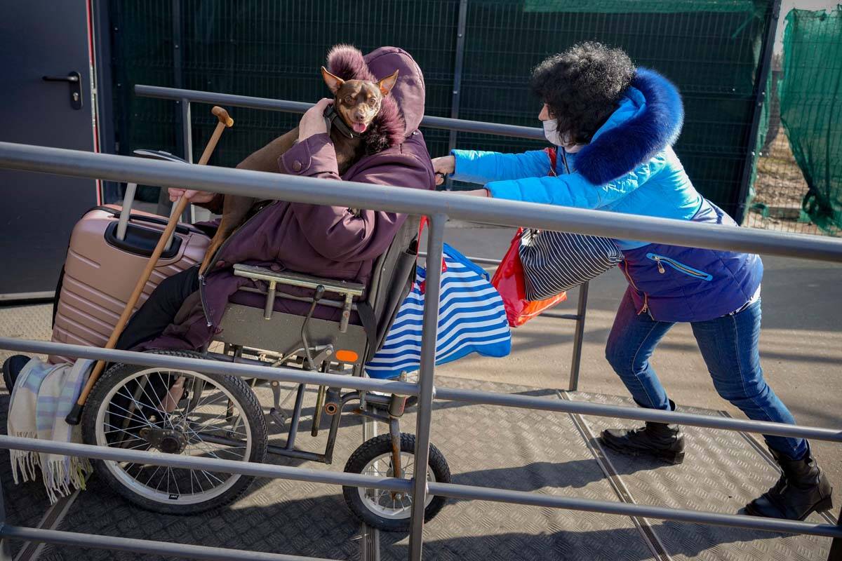 A woman pushes a wheelchair carrying an elderly woman holding a dog from pro-Russian separatist ...