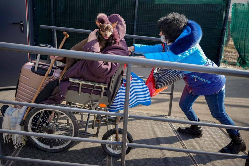 A woman pushes a wheelchair carrying an elderly woman holding a dog from pro-Russian separatist ...