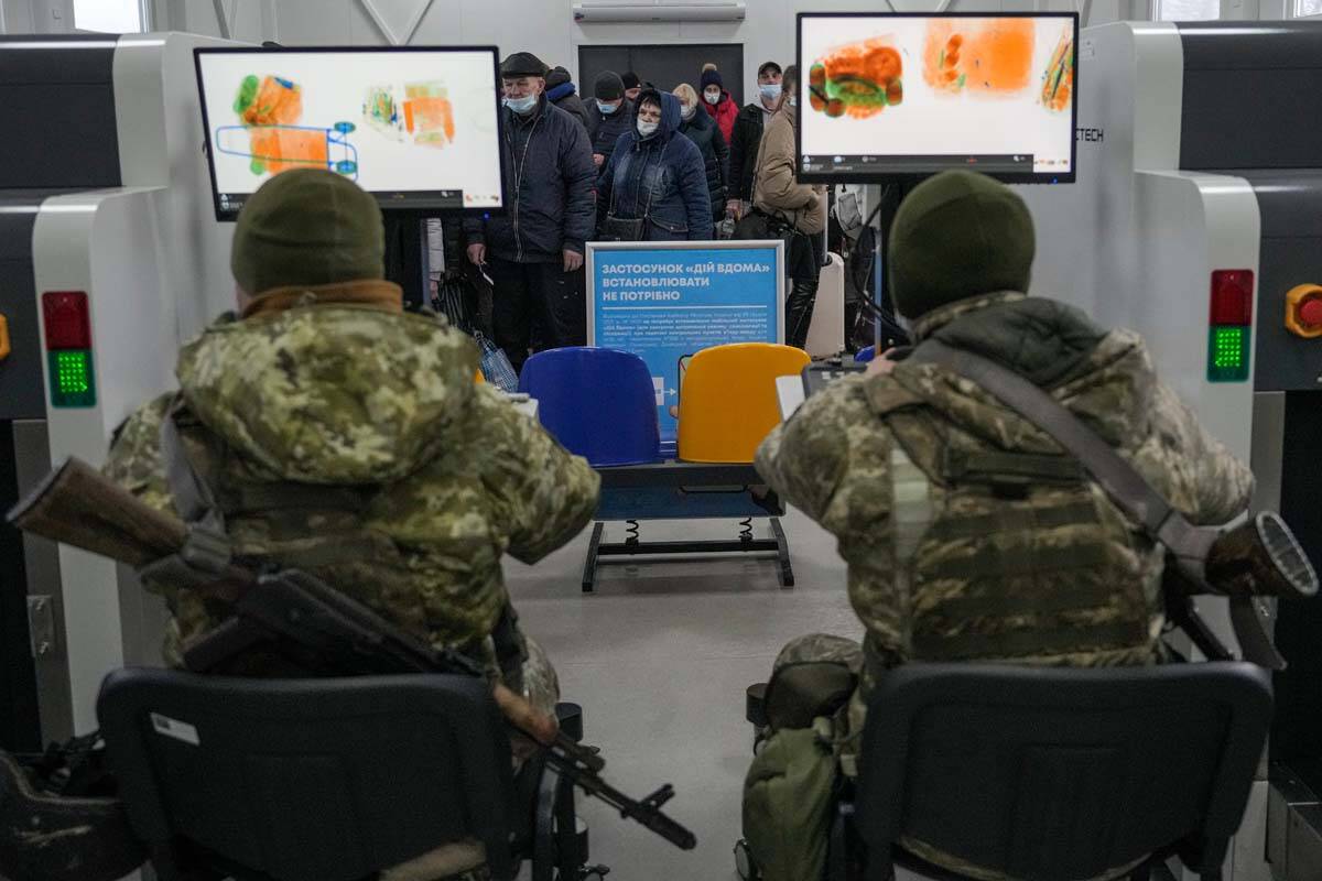 Ukrainian servicemen scan belongings of people crossing from Ukrainian government controlled ar ...