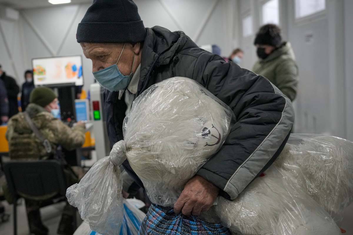 A man holds a giant stuffed toy while crossing from Ukrainian government controlled areas to pr ...