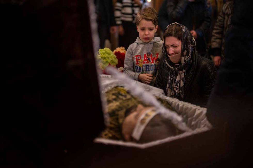 A woman and a boy react next to the body of Ukrainian Army captain Anton Sydorov, 35, killed in ...