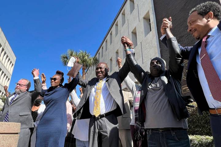 The family and attorneys of the Ahmaud Aubery raise their arms in victory after all three men w ...