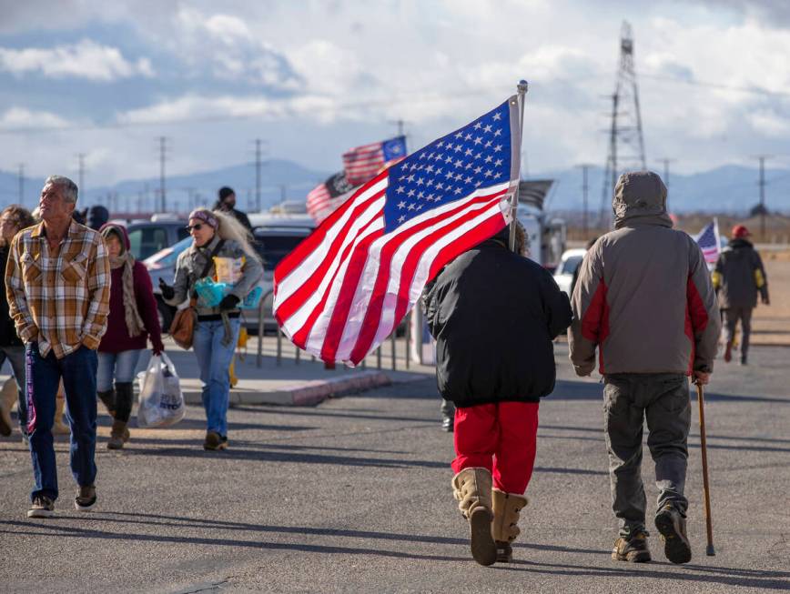 Attendees carry flags and make their way along during a departure event for The People’s ...