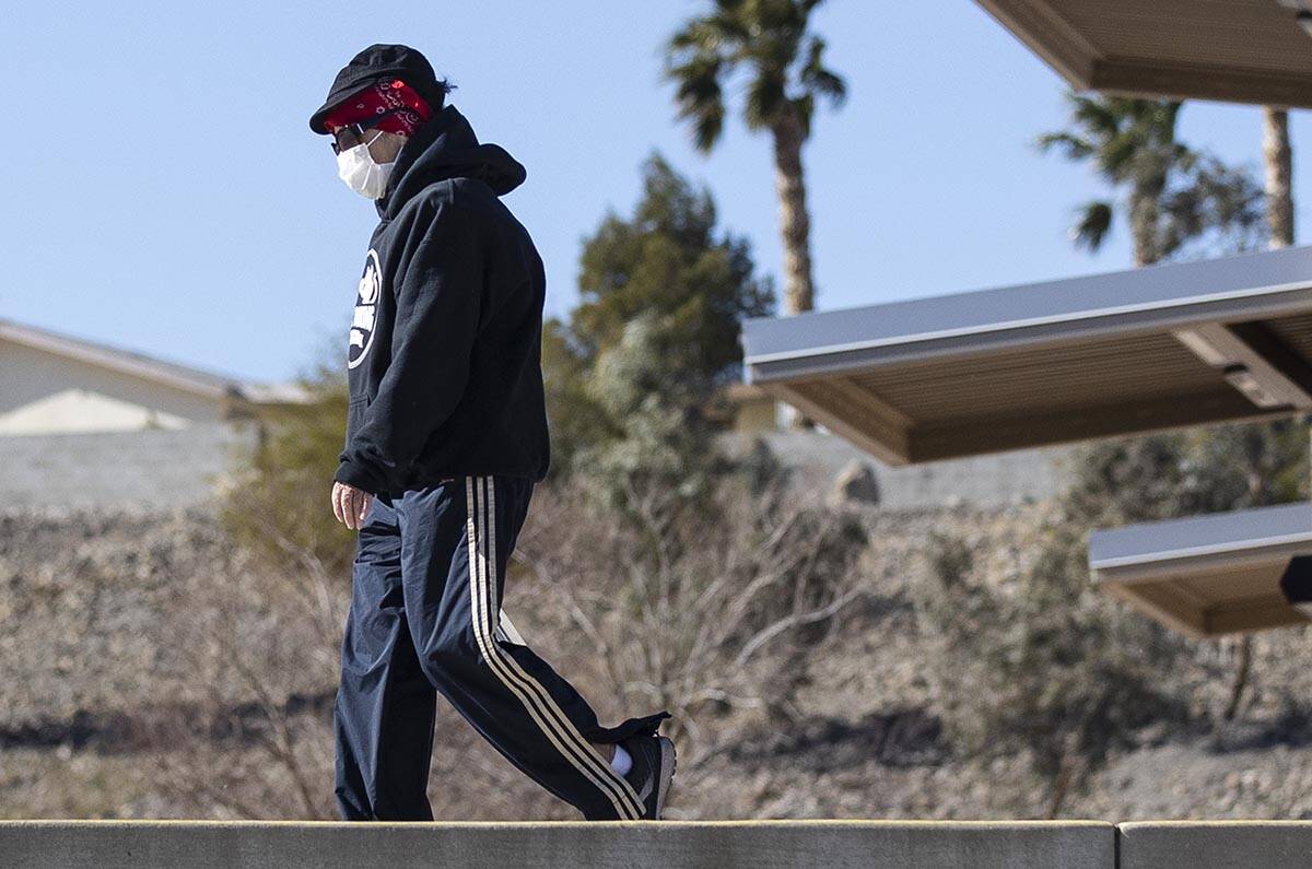 Juan Young of Henderson bundled up as he walks during a windy day at Cornerstone Park on Tuesda ...